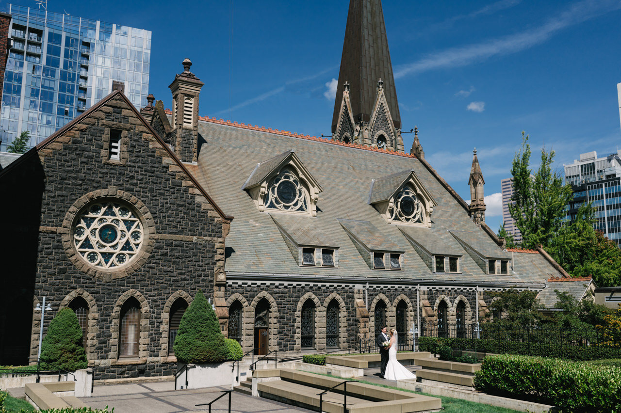  Bride and groom stand in first presbyterian church courtyard in downtown portland architecture 