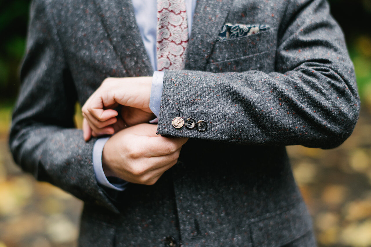  Closeup of groom copper cufflinks and grey and red-flecked suit 