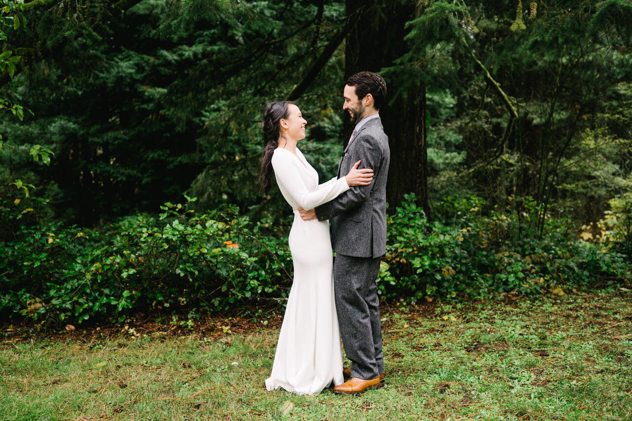  Bride and groom laugh at each other in forest intimate moment 