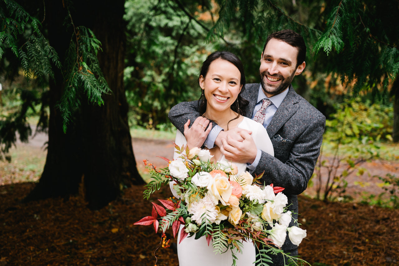  Bride and groom laughing together under large redwood tree 