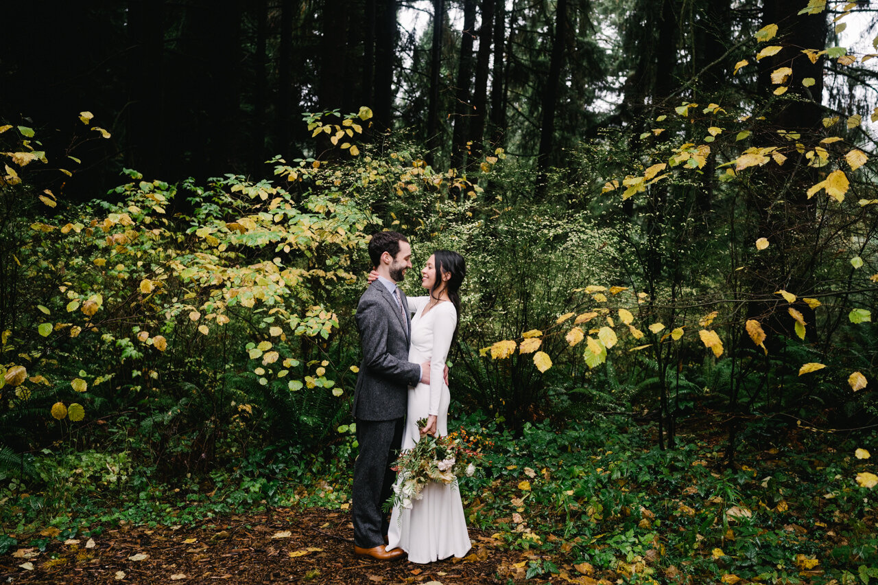  Bride and groom wrapped around each other standing in fall forest scene in portland 