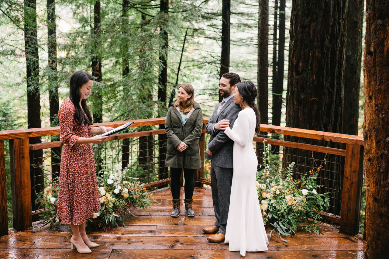  Bride sister reading at wedding ceremony on redwood deck in the rain 
