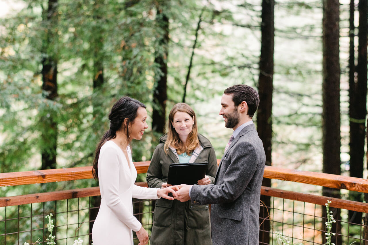  Groom places ring on bride's finger on redwood deck wedding 