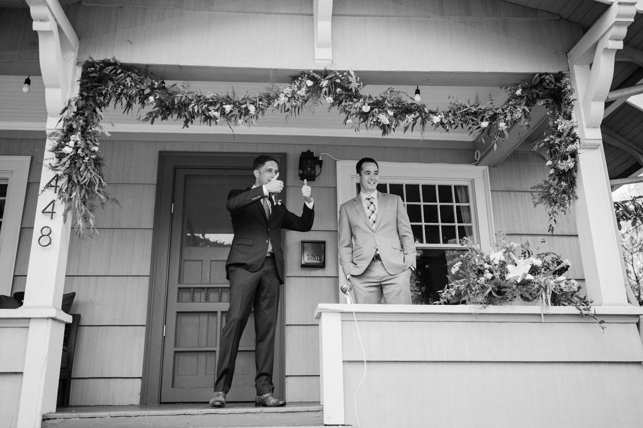  Groom gives thumbs up with best man on front porch wedding 