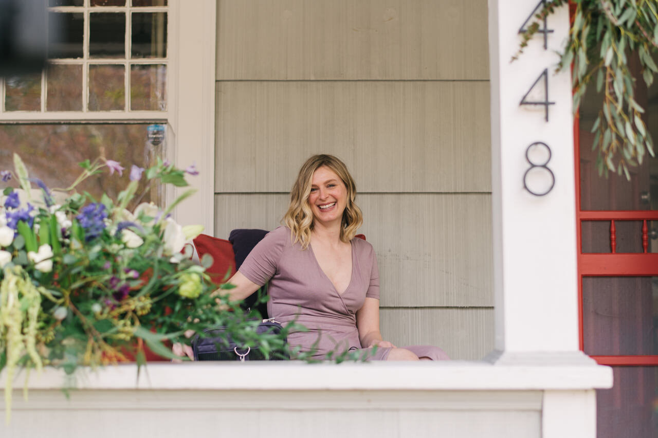  Maid of honor laughs as she sits down for wedding ceremony on front porch 