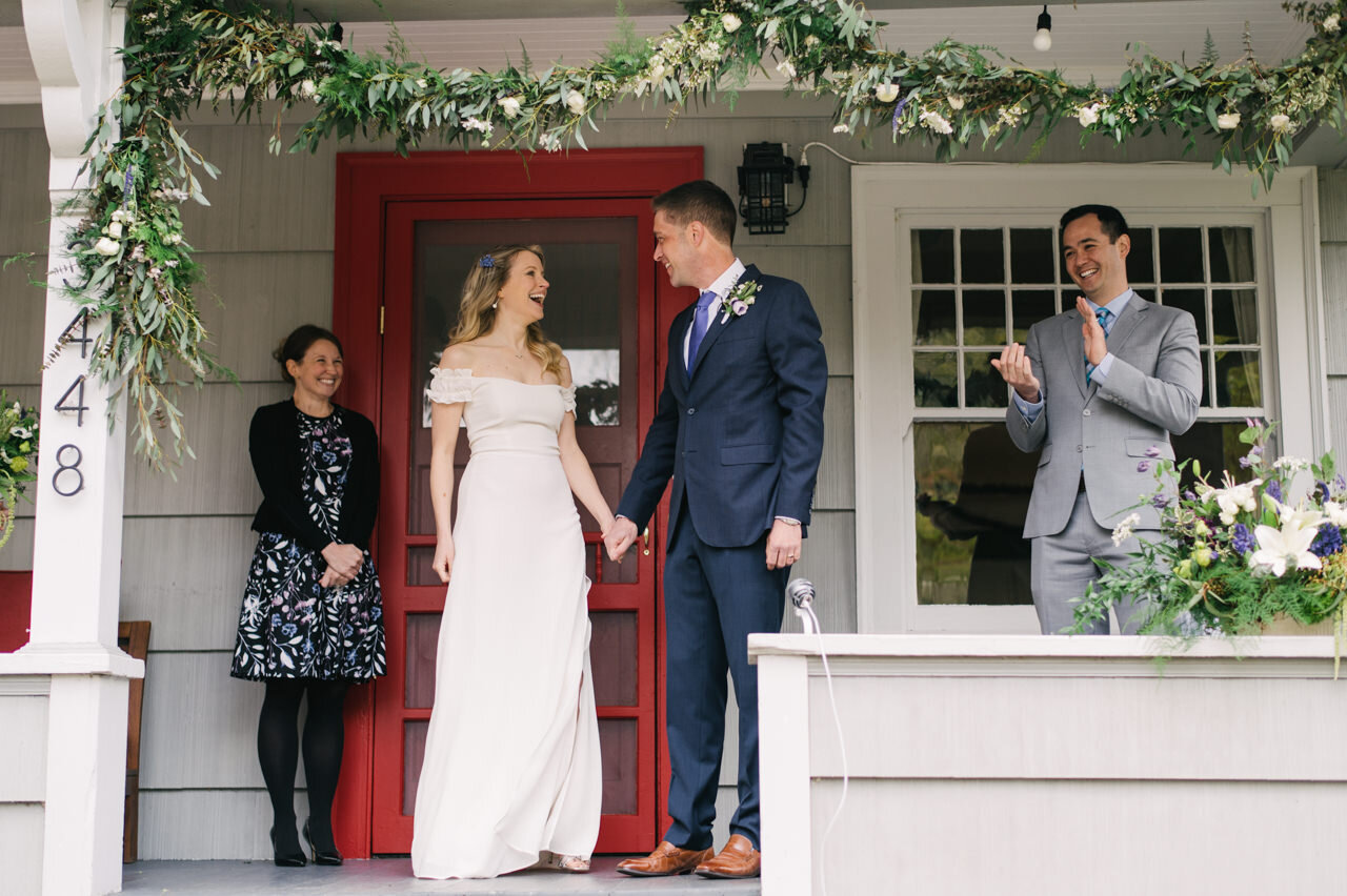  Groom and bride laugh with each other after wedding ceremony on front porch 