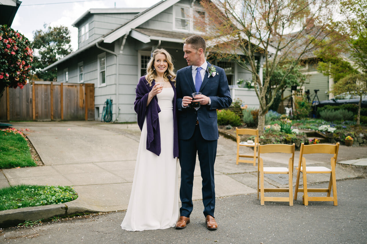  Wedding couple talks with drinks in front of home 