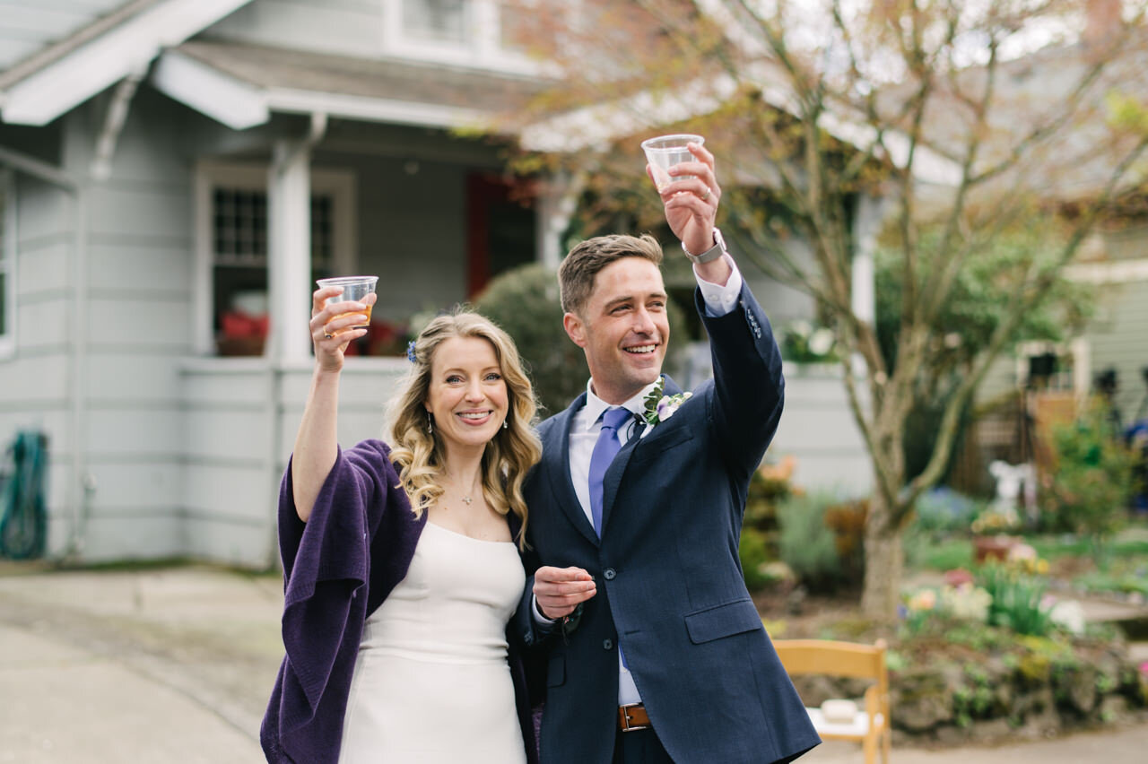  Bride and groom toast on the street in front of their home 