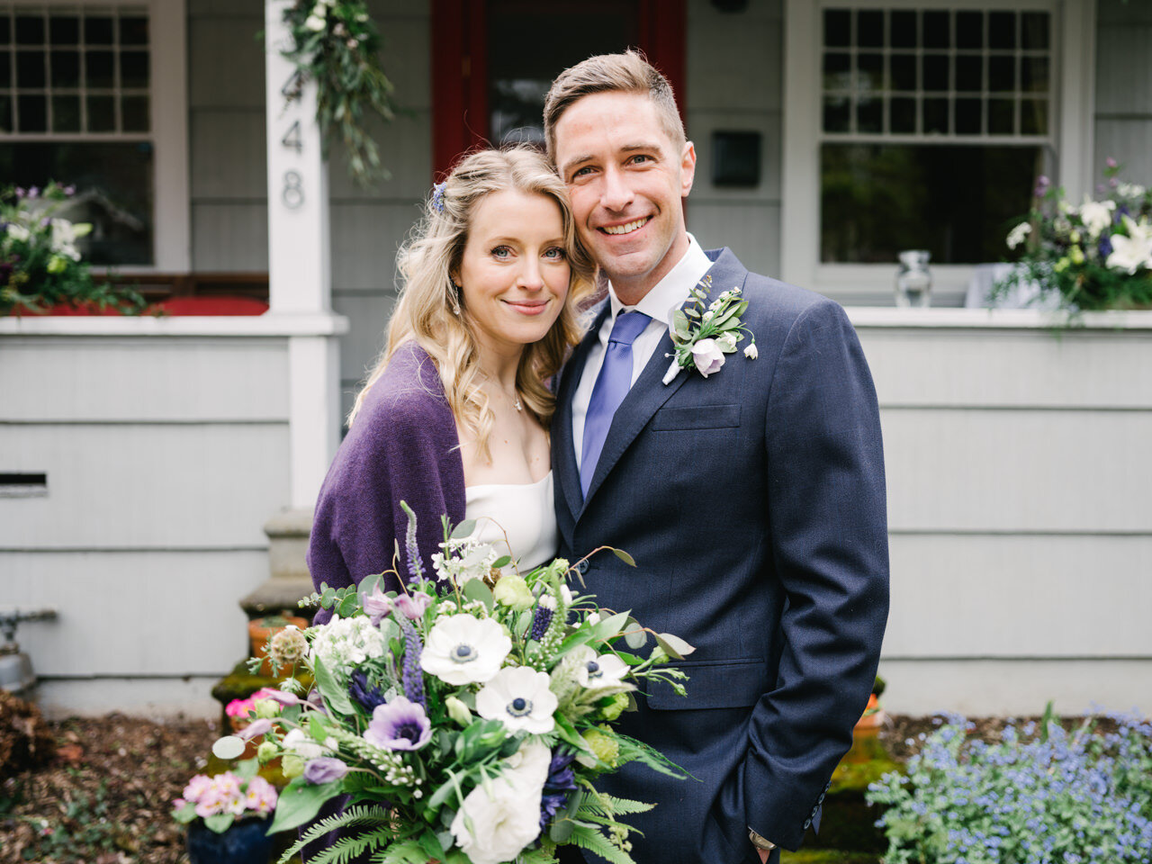 Bride and groom smile together during classic wedding portrait in front of their portland home 