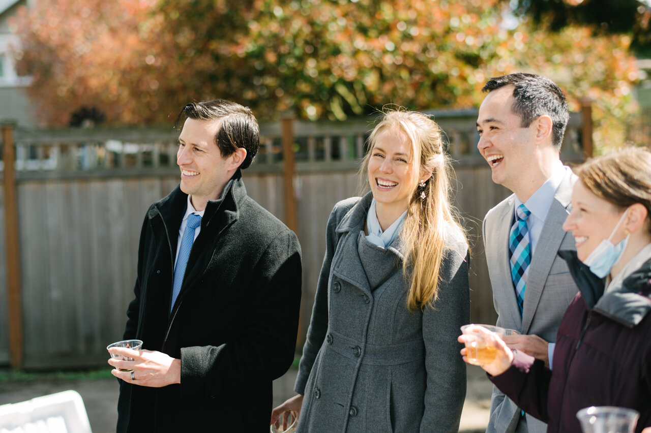  Wedding guests in overcoats laugh during candid moment 