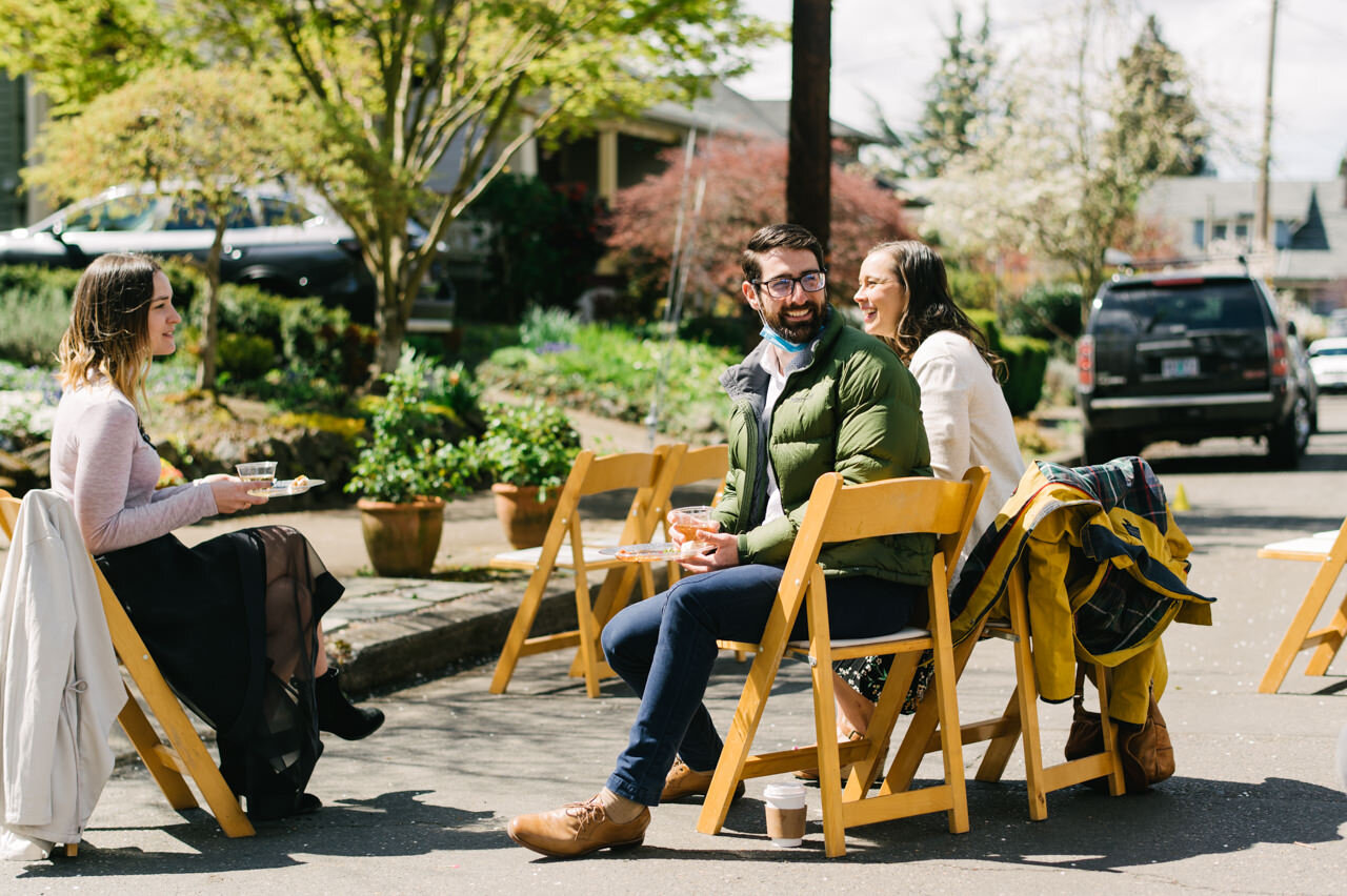  Wedding guests chat on wood folding chairs in street of portland wedding 