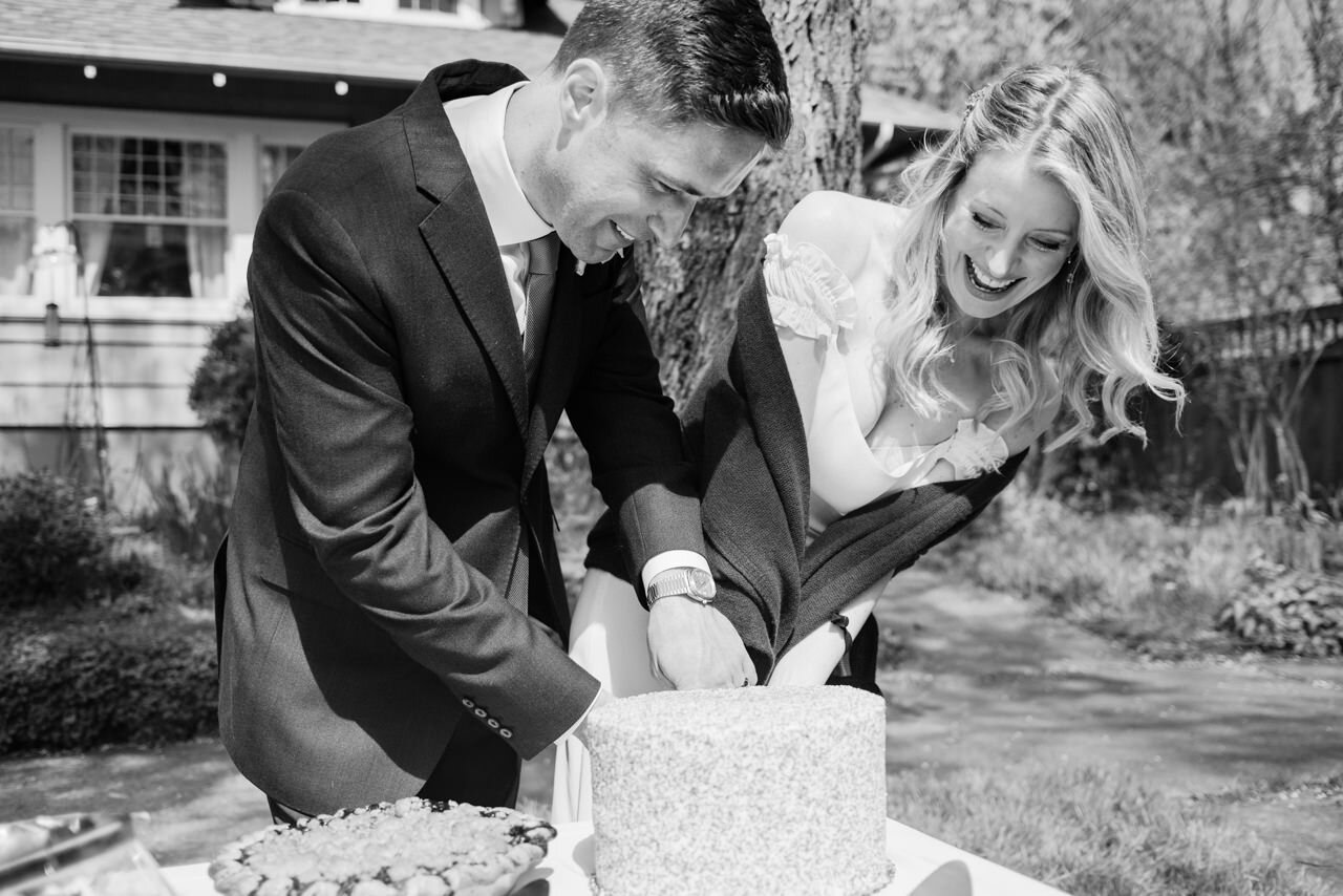  Bride and groom struggle to cut the cake in black and white photograph 