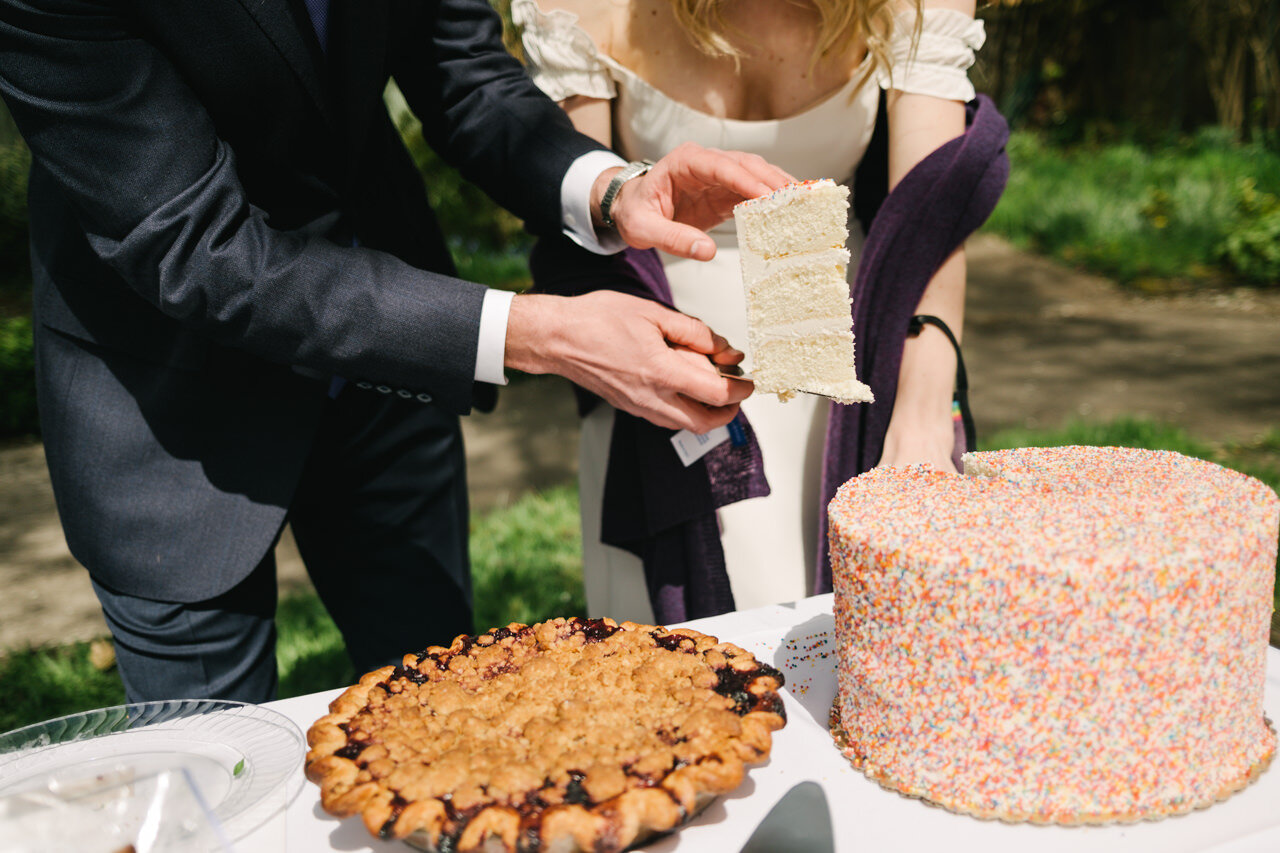  Groom holds giant piece of white cake outside 