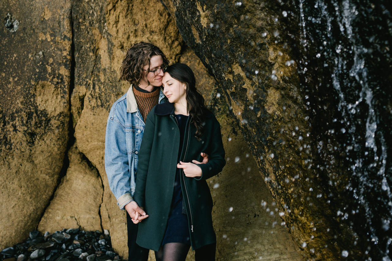  Engaged couple shares tender moment under hug point waterfall 