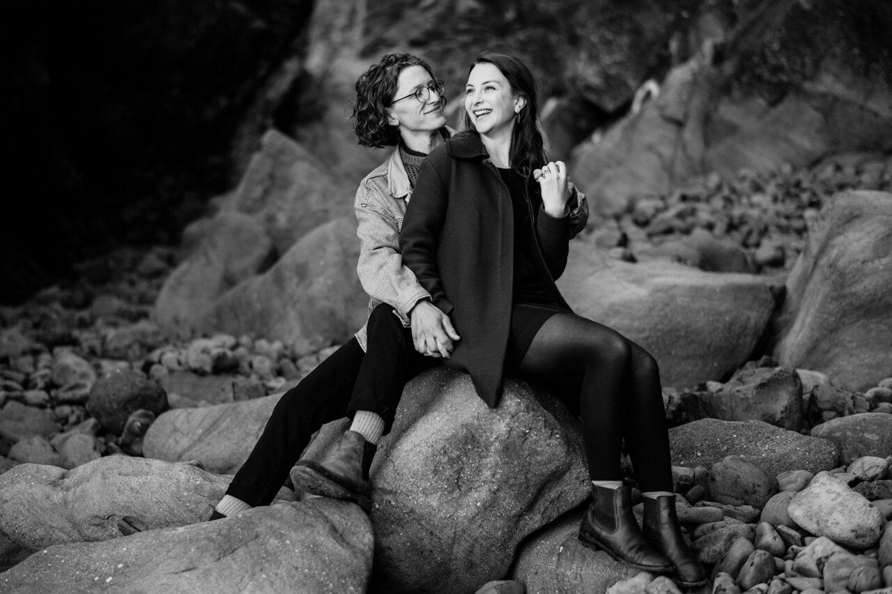  Girl laughs while sharing sitting on a rock on the coast 