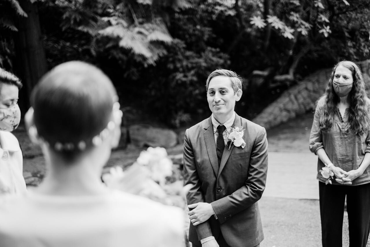  Groom looks at bride during masked elopement 
