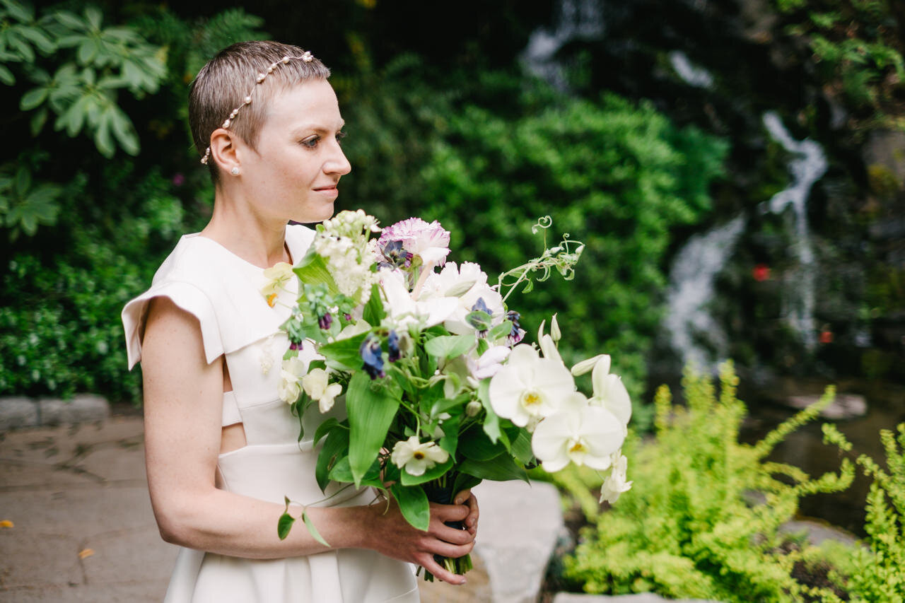  Bride in custom dress stands in front of waterfall at crystal springs elopement 