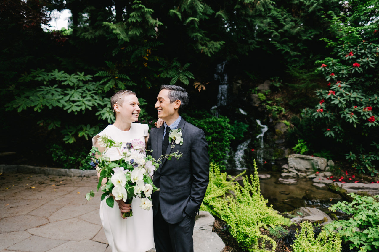  Laughing couple stand in front of Jane Martin ceremony site at crystal springs with green and waterfall backdrop 