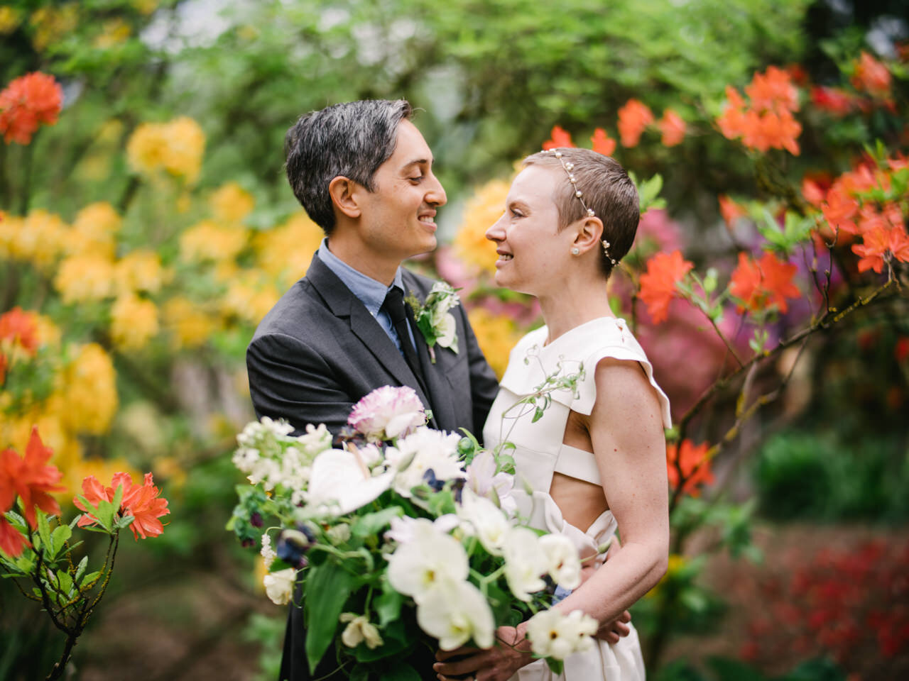  Bride and groom romantic gaze in front of swirly orange and yellow flowers 