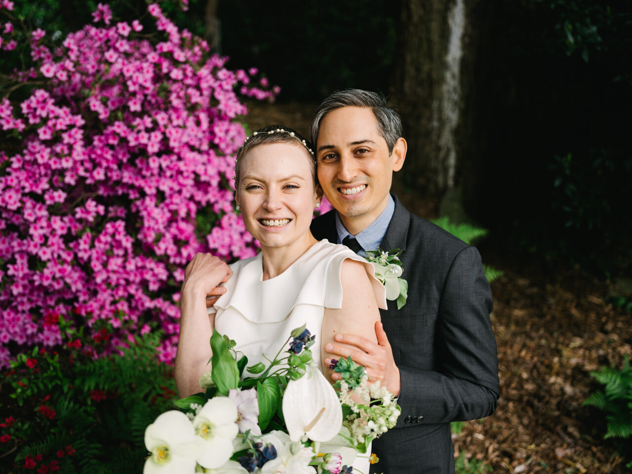  Bride and groom laughing in front of pink azalea bushes 