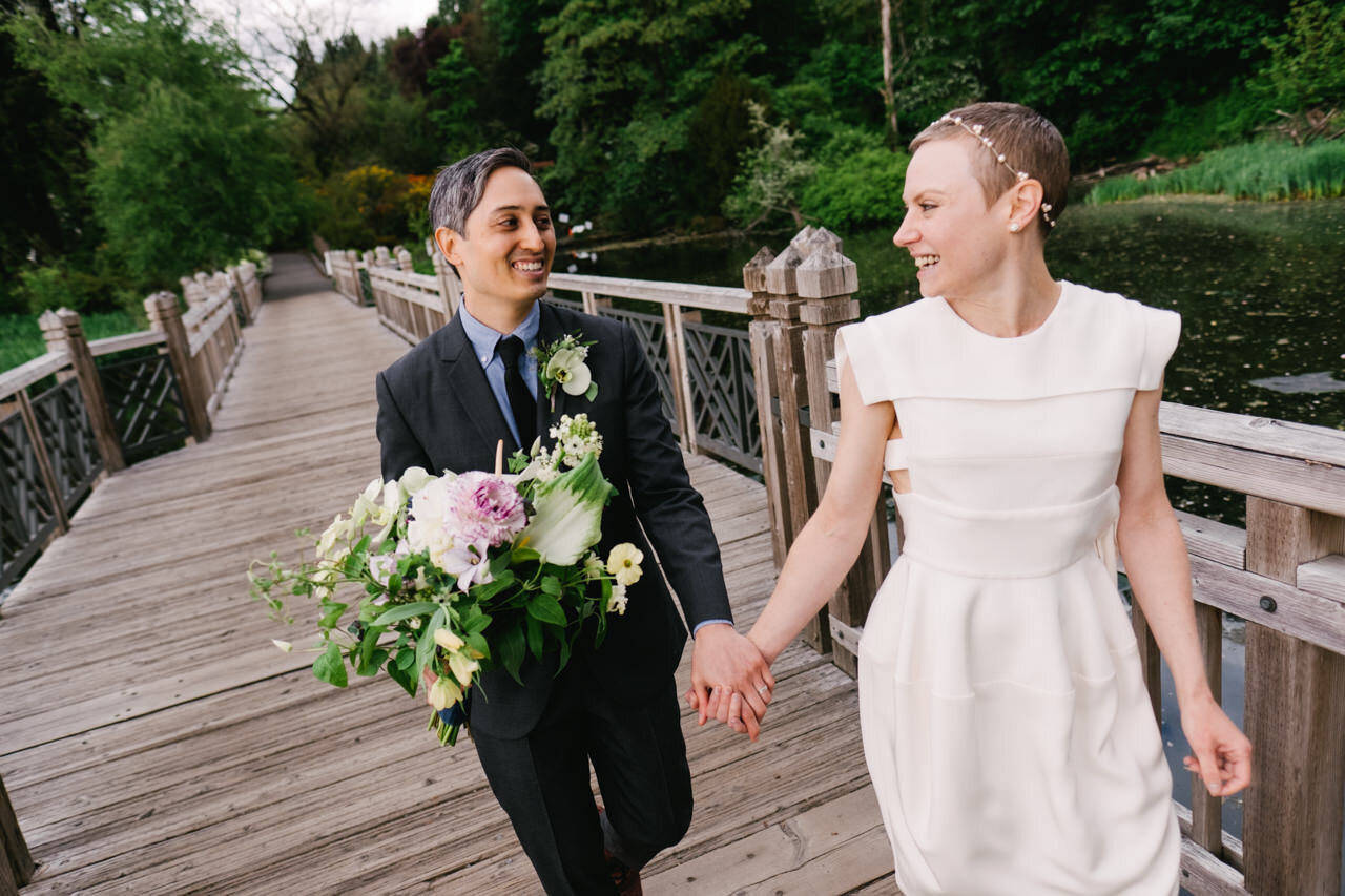  Bride and groom holding hands across crystal springs bridge laughing 