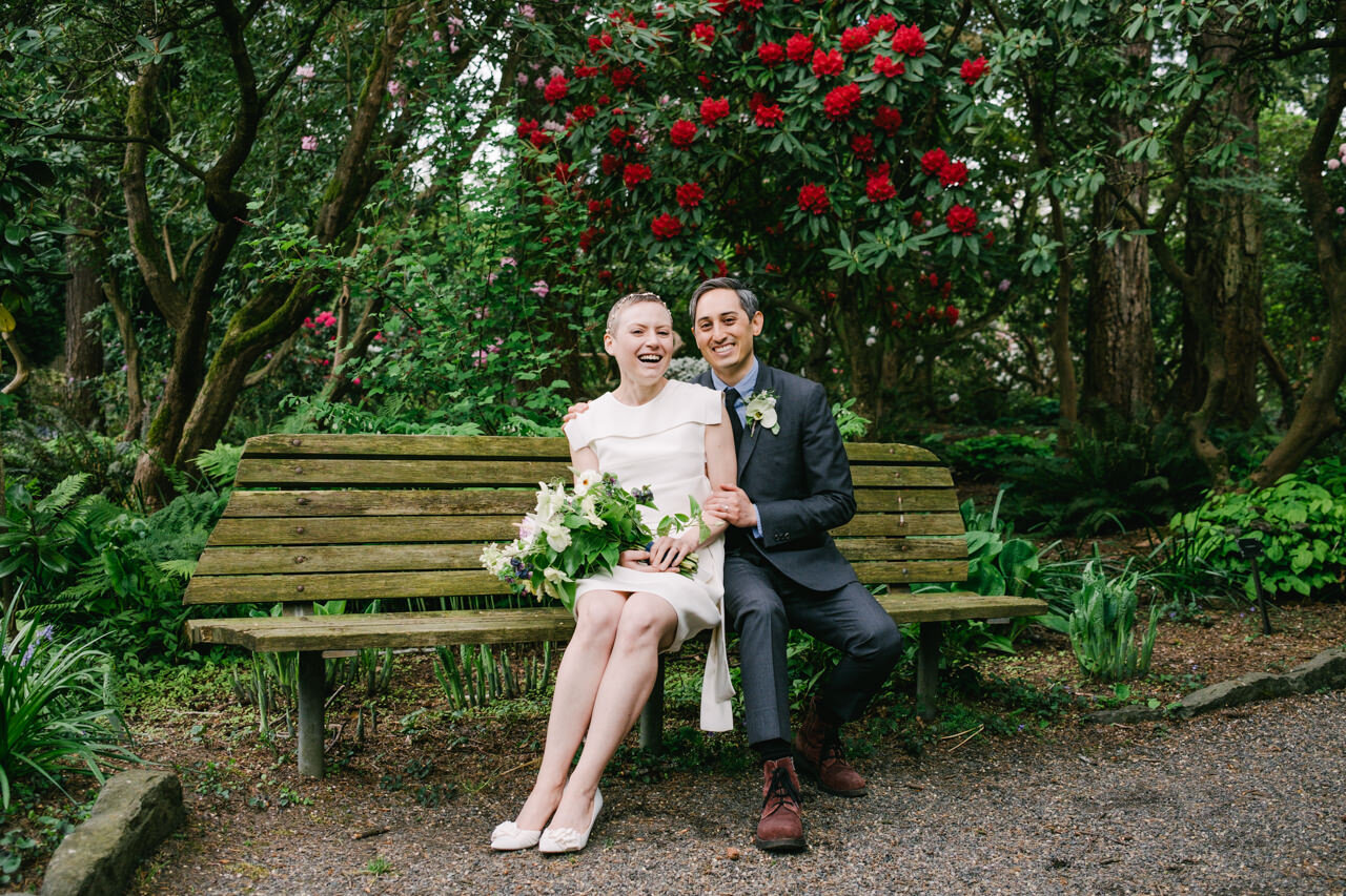 Elopement in rhododendron grove on bench while bride and groom laugh 