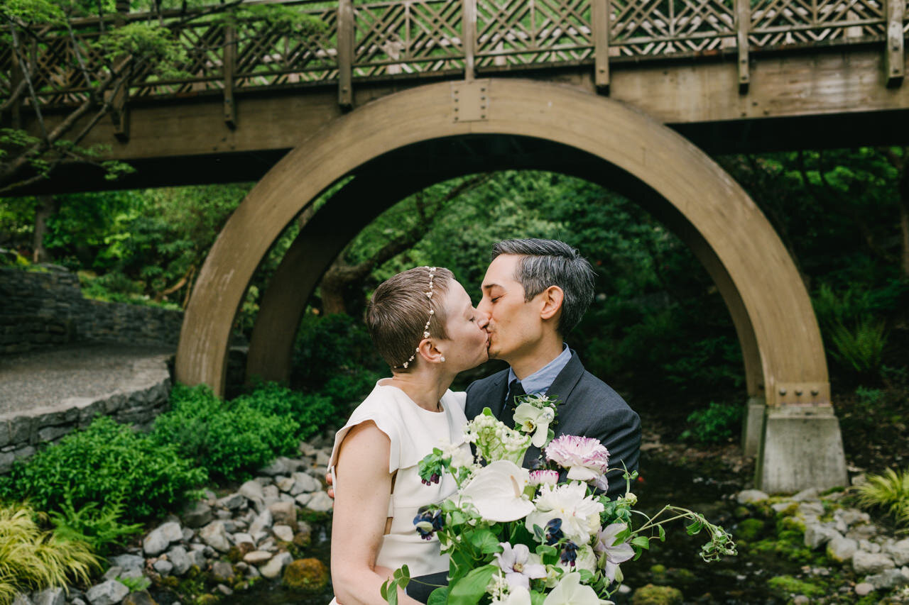  Kiss under crystal springs bridge with wedding couple holding bouquet 