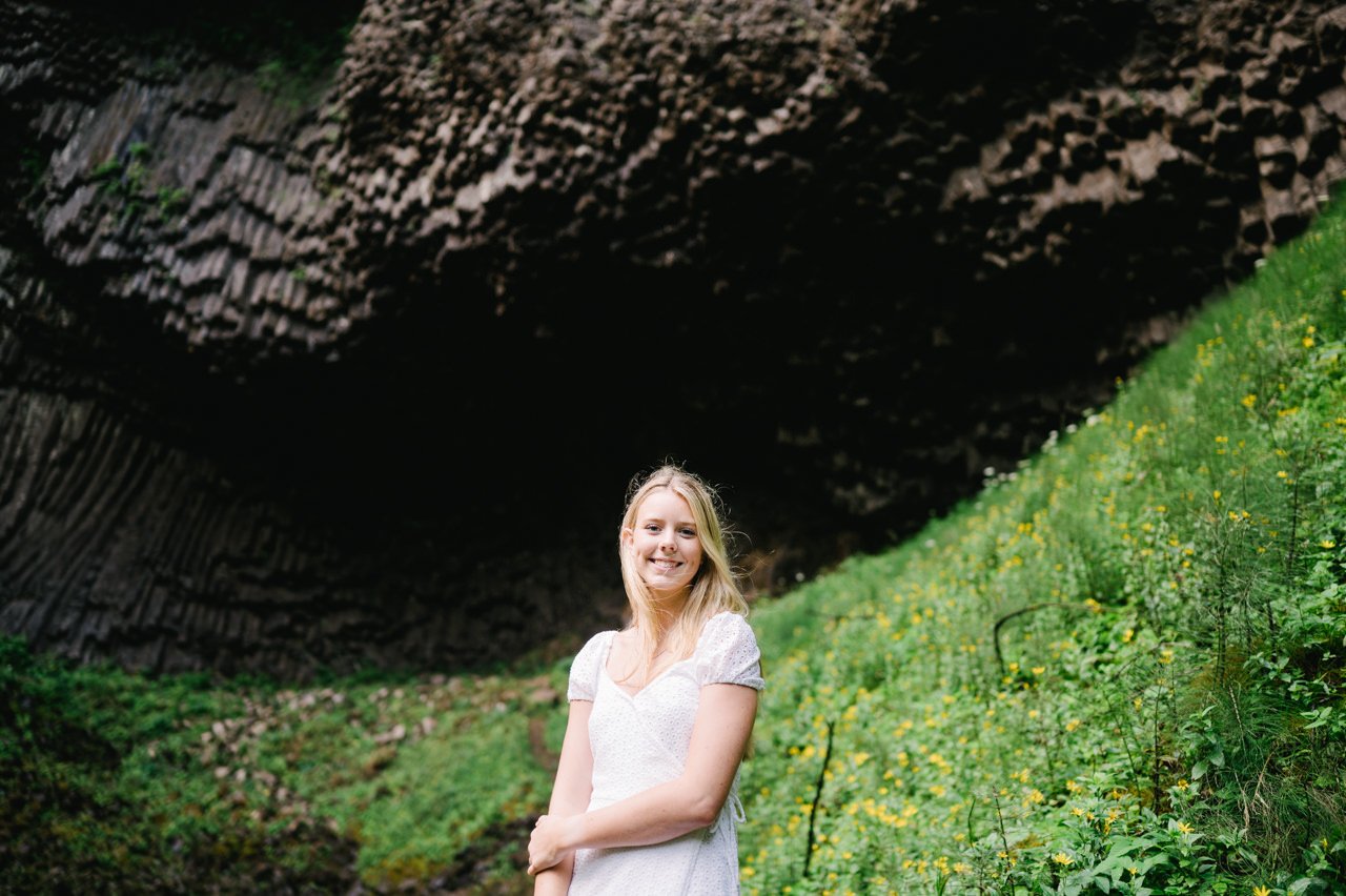  Girl smiling with basalt waterfall cavern behind her 