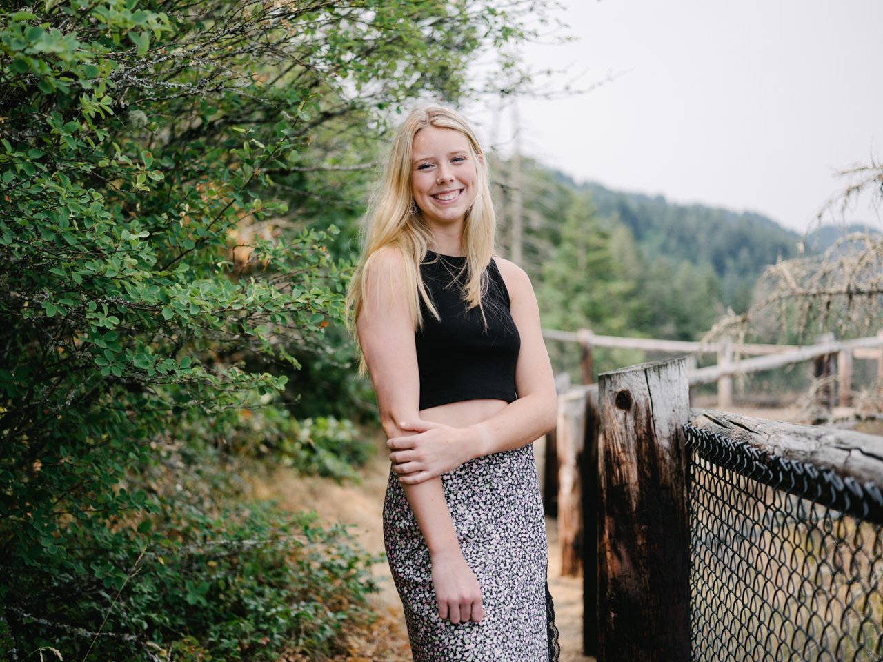  Smiling high school student by fence line and black and white skirt 