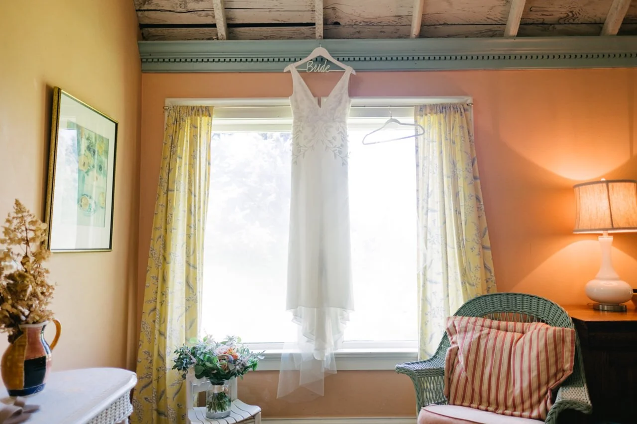  Wedding dress hanging in window with orange and yellow walls 