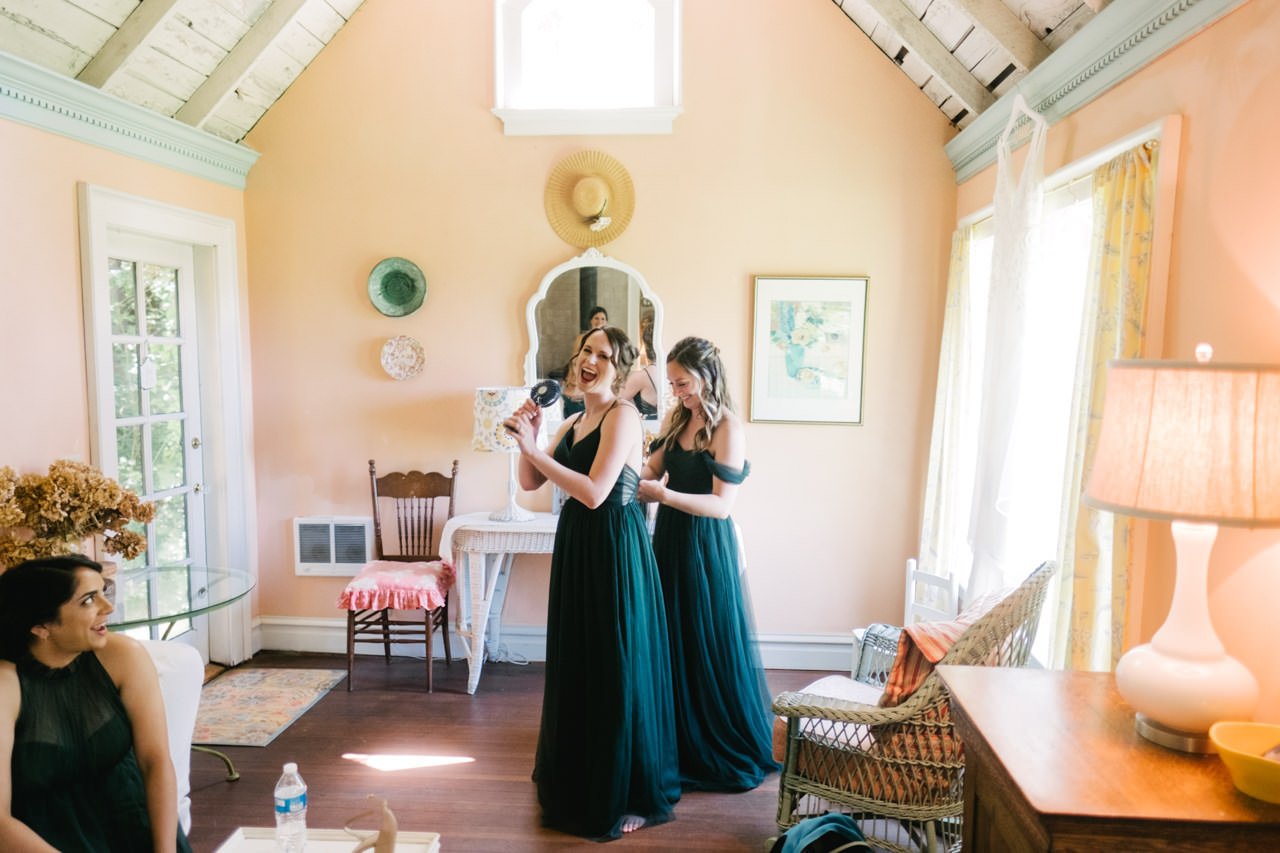  Bridesmaids pretend to sing into fan on hot day in bridal room 