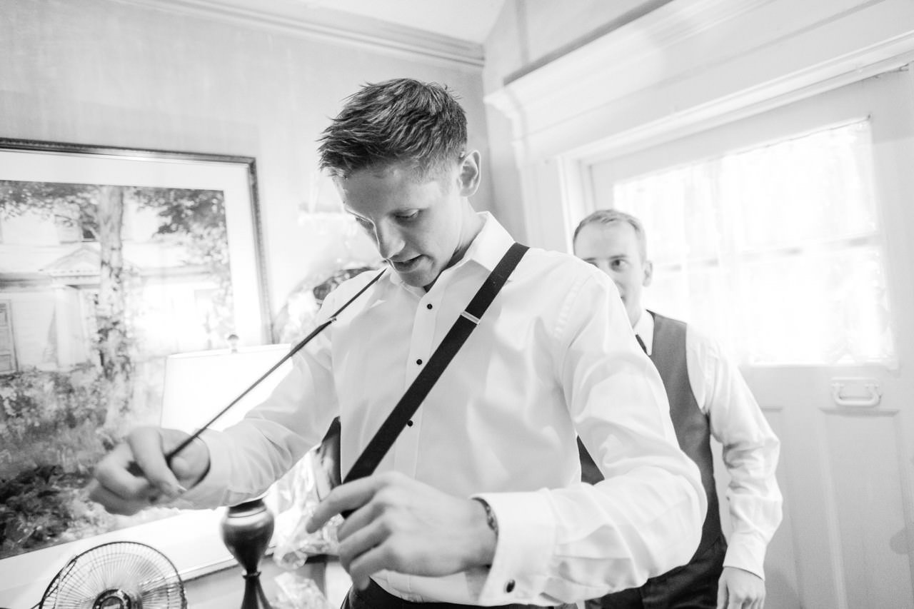  Black and white photograph of groom stretching out suspenders 