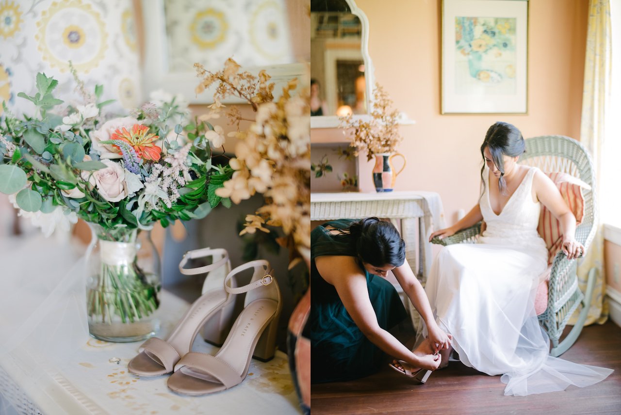  Bride sits in chair while bridesmaid adjusts her shoes 