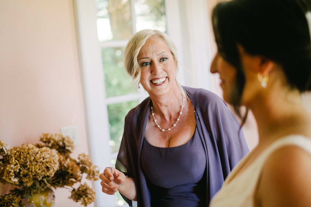  Candid moment of mother of bride in purple dress laughing with bride 