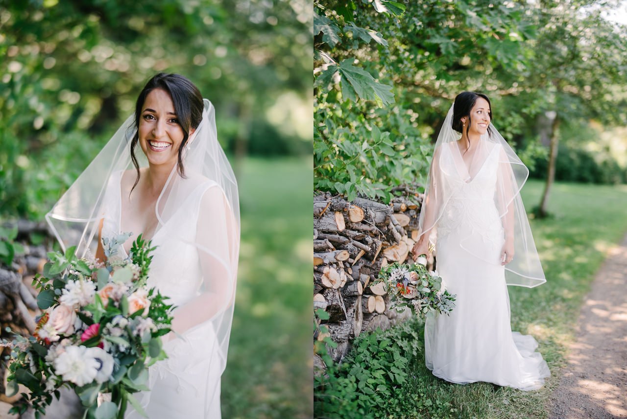  Bride laughing with veil blowing around her while standing next to wood pile 