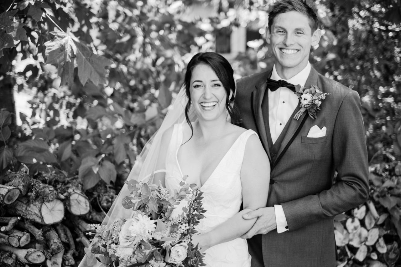  Bride and groom laughing in black and white moment in front of wood kindling 