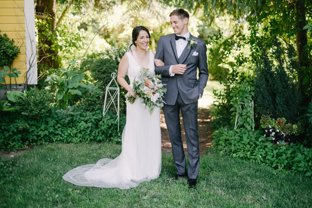  Candid moment of bride and groom laughing together by yellow house 