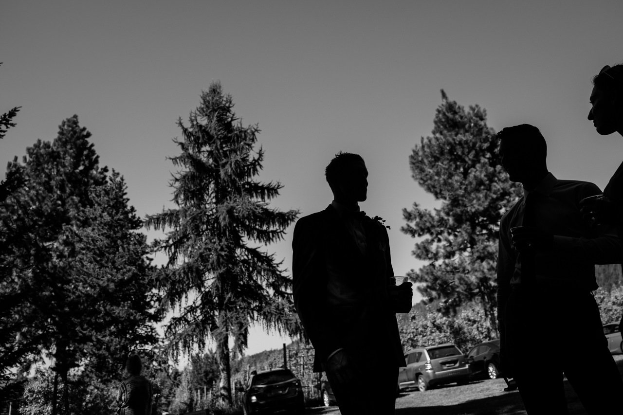  Silhouette of groom sharing a drink with wedding guests 