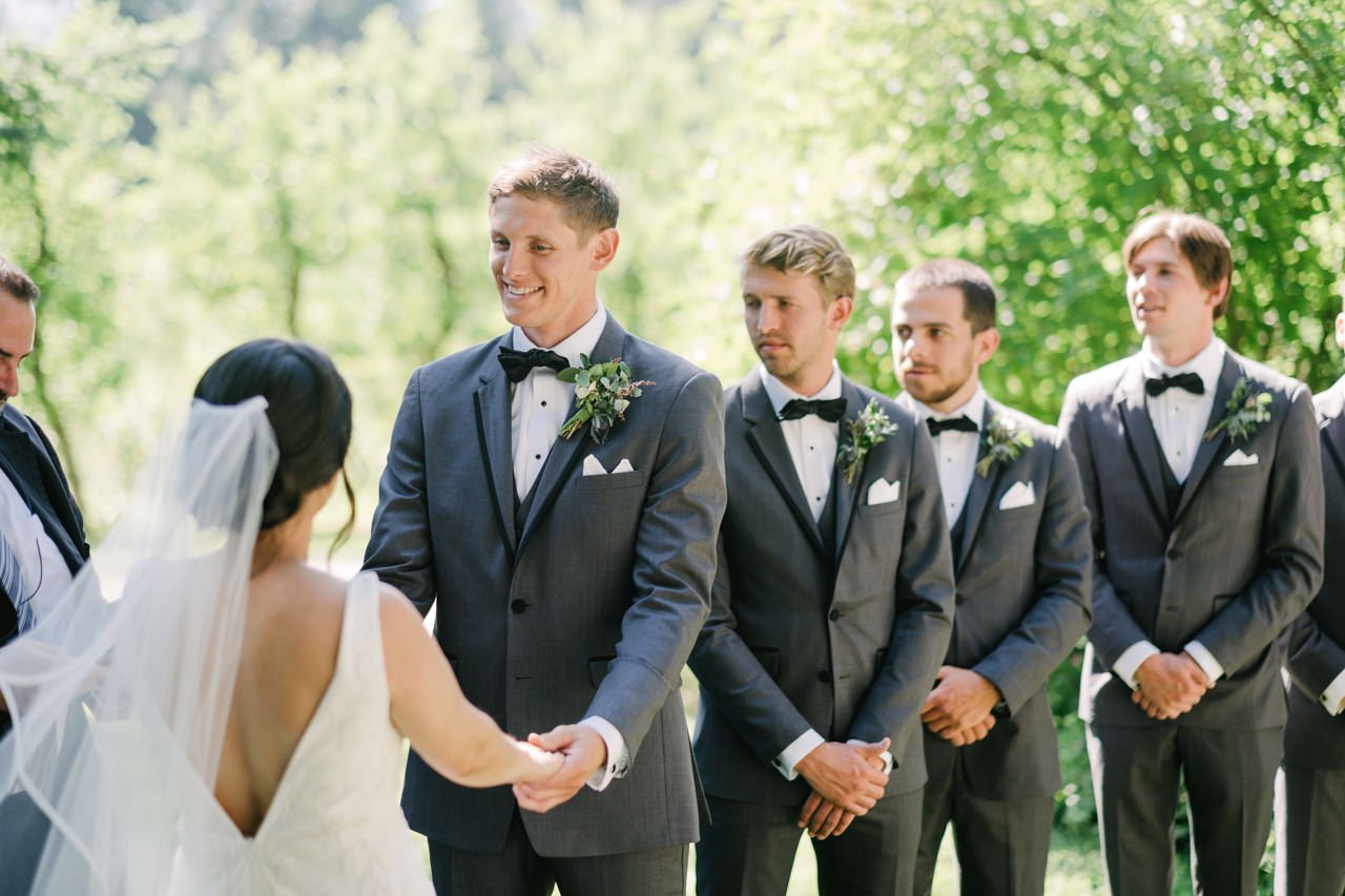  Groom gives look to bride in green wedding grove 