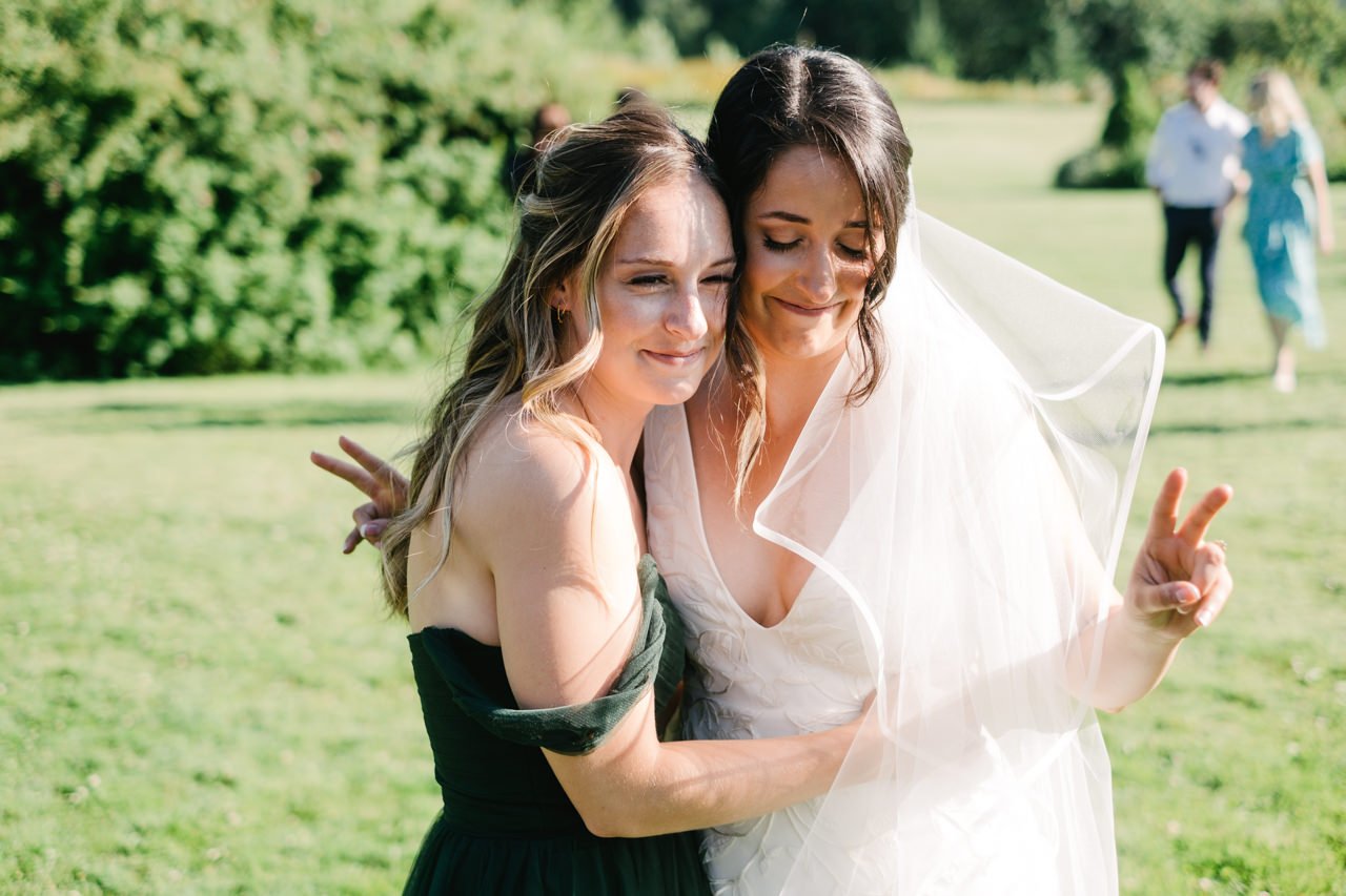  Bride throws peace signs while hugged by bridesmaid 