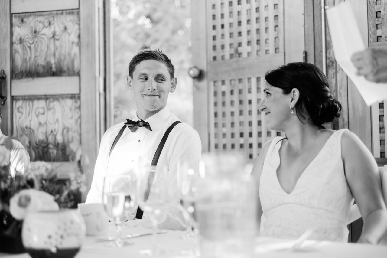  Bride and groom share a knowing look during wedding toasts in the apple house 