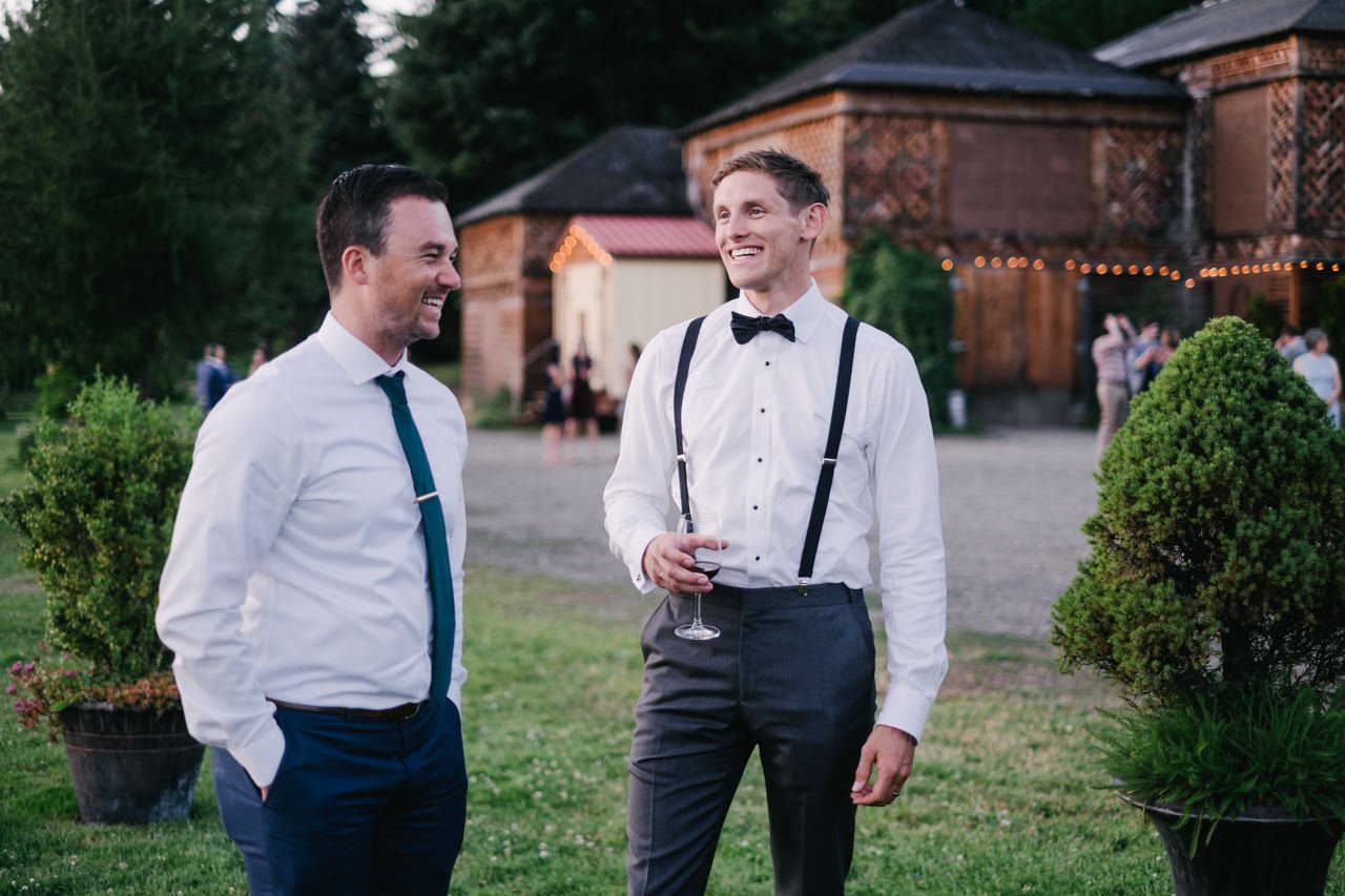  Groom and guest laugh in casual evening cocktail hour 