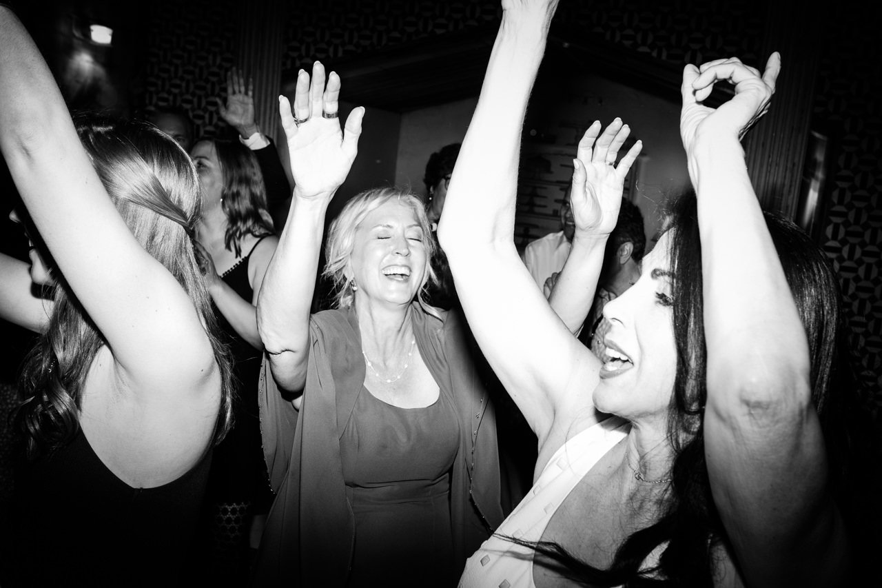  Mother of bride throws hands up while dancing at wedding reception 