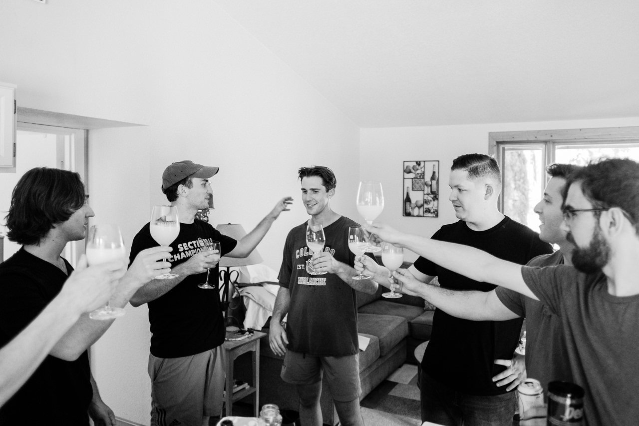  Black and white photo of groomsmen toasting with wine glasses 