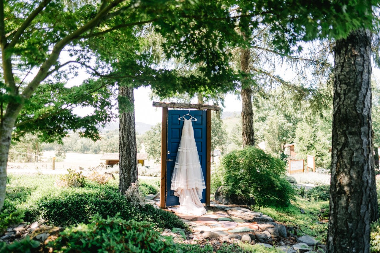  Bride wedding dress hangs off blue door at reustle prayer rock vineyard 