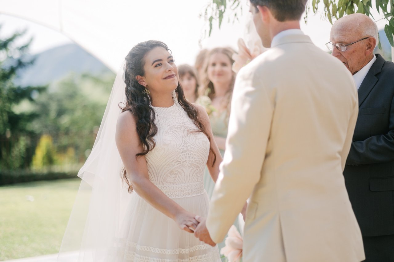  Bride smiles at groom while officiant speaks 