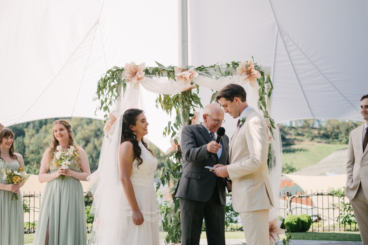  Bride laughs while groom prepares vows 