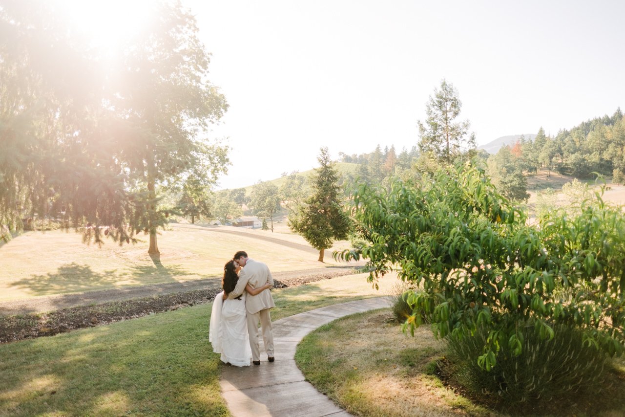  Bride and groom kiss in sunlight on bath with southern Oregon valley 