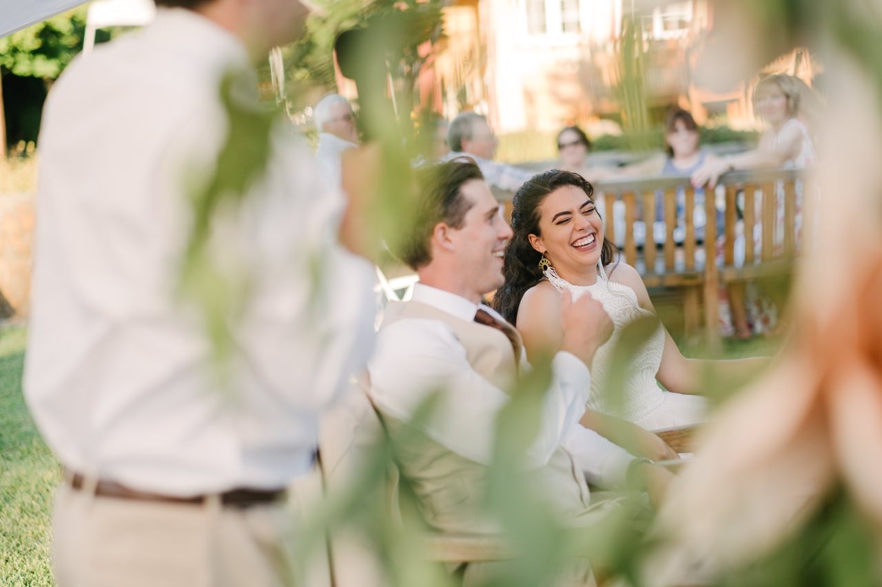  Bride and groom laugh through floral backdrop 