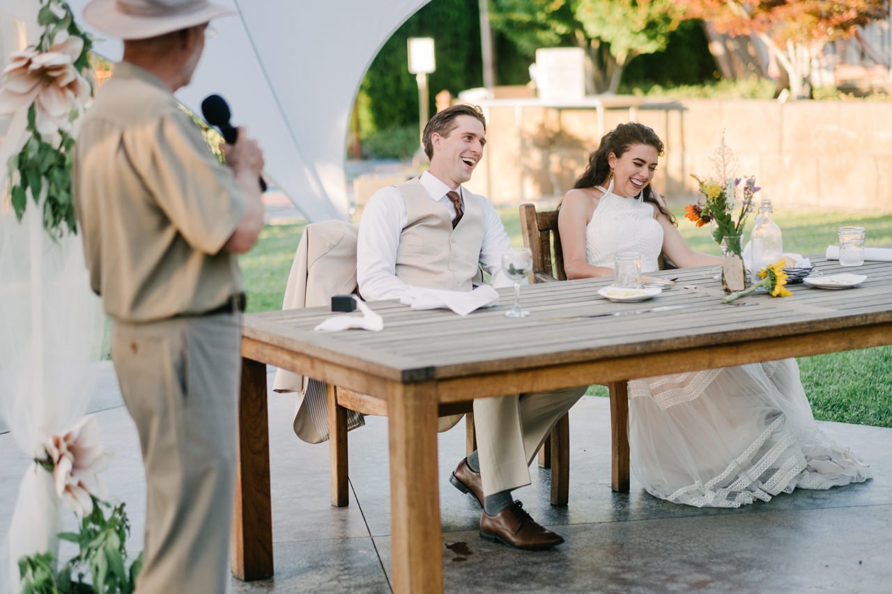  Toast by father of bride makes couple laugh on large picnic table 